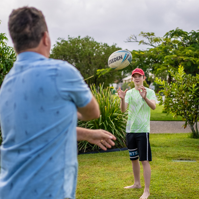 man passing football with teenager