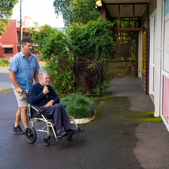 Support worker pushing elderly man in wheelchair