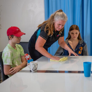 Cleaner wiping down table in front of kids